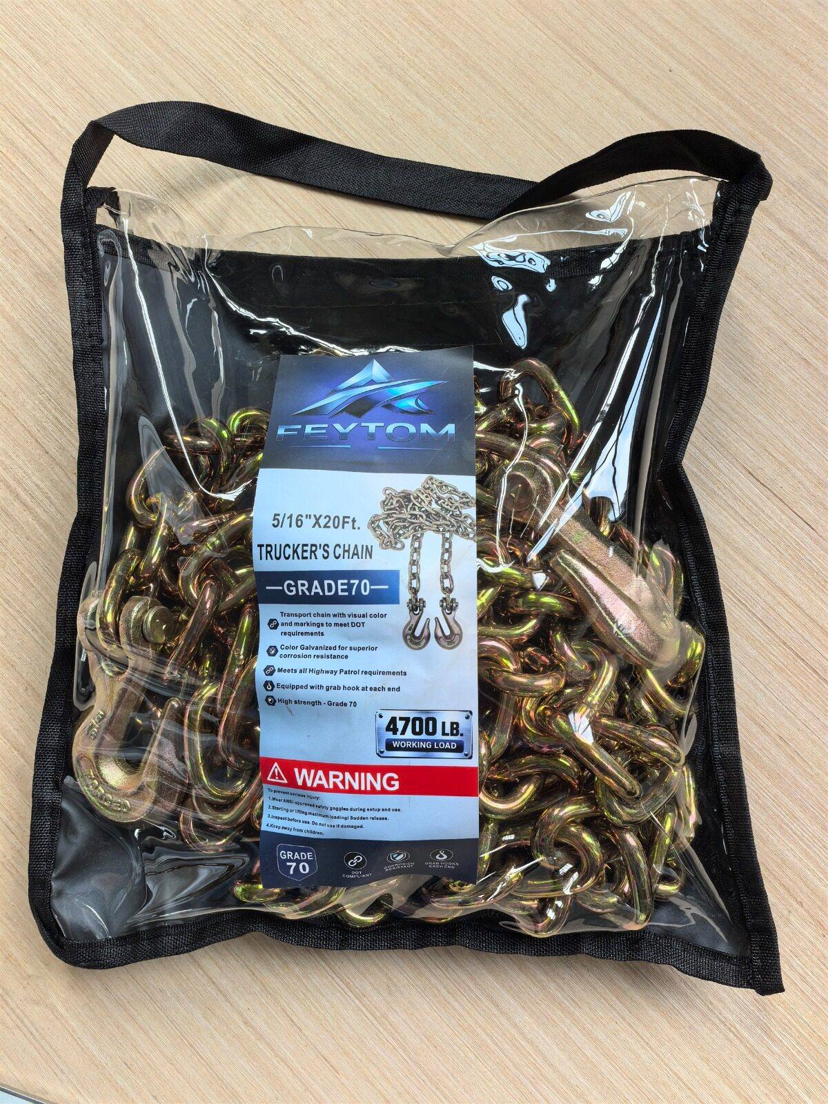 A Feytom Grade 70 trucker's chain coiled inside a clear PVC carry bag with a black fabric handle. The yellow-zinc chain and its two grab hooks are visible through the bag; the printed insert reads 5/16 inch by 20 feet, Grade 70, 4,700 lb working load.